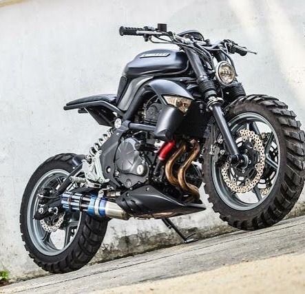 a black motorcycle parked next to a white wall