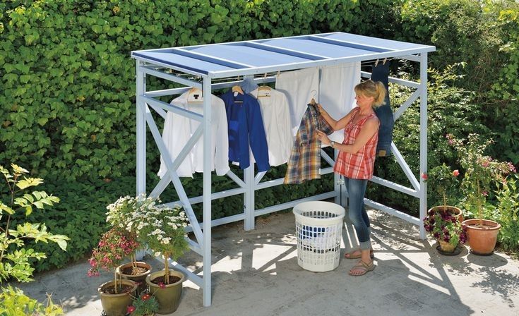 a woman hanging out clothes on a clothes line in the garden with her laundry basket