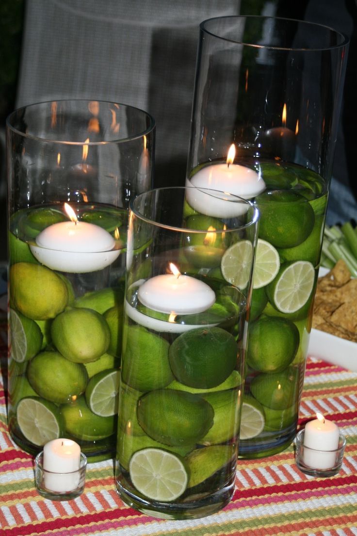 limes and candles are in glass vases on a table