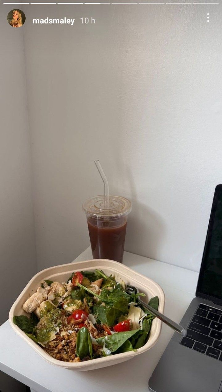 a salad in a bowl next to a laptop on a desk with a cup of coffee