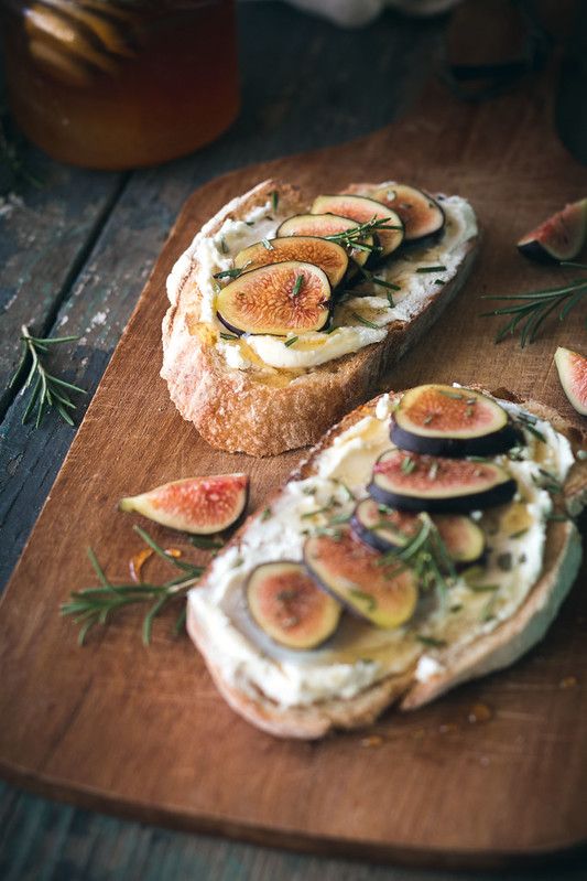 bread topped with sliced figs and cheese on a cutting board