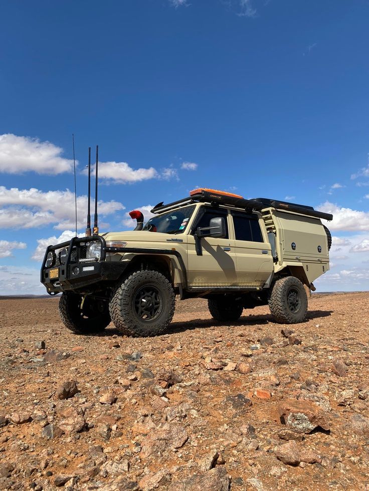 an off - road vehicle parked in the desert with its roof open and two radio antennae on top