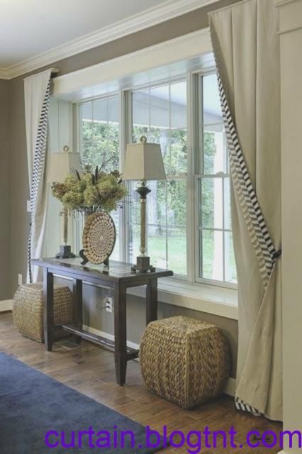 a living room filled with furniture next to a window covered in curtains and drapes