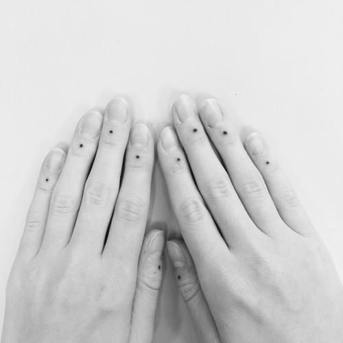 two hands holding each other with small dots on their fingers