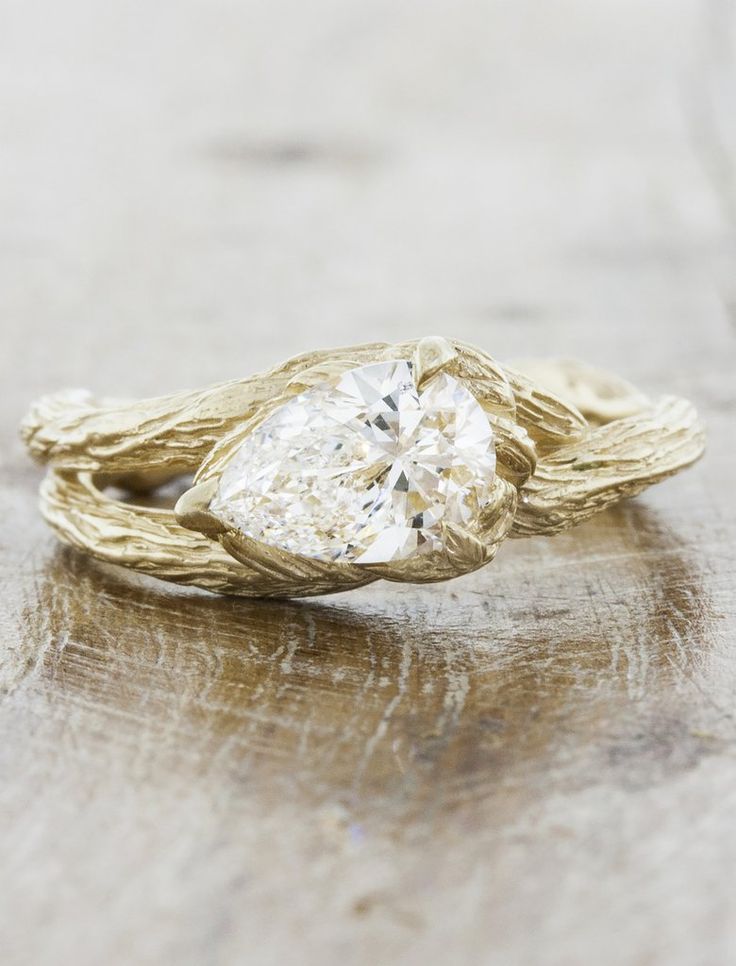 a gold and white diamond ring sitting on top of a wooden table