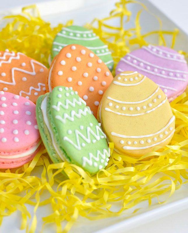 colorful decorated easter eggs sitting on top of yellow shredded grass with the words, how to decorate an easter egg macarons