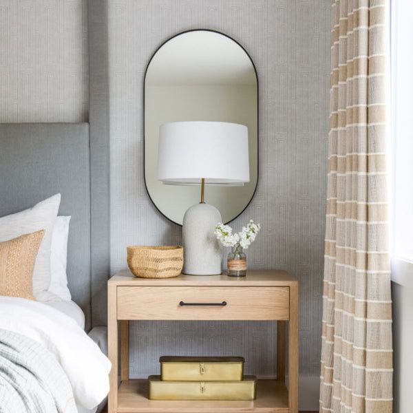 a bedroom with a bed, mirror and lamp on the side table next to it