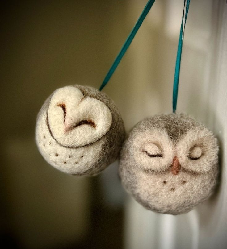 an owl ornament hanging from a hook on a wall with two eyes closed