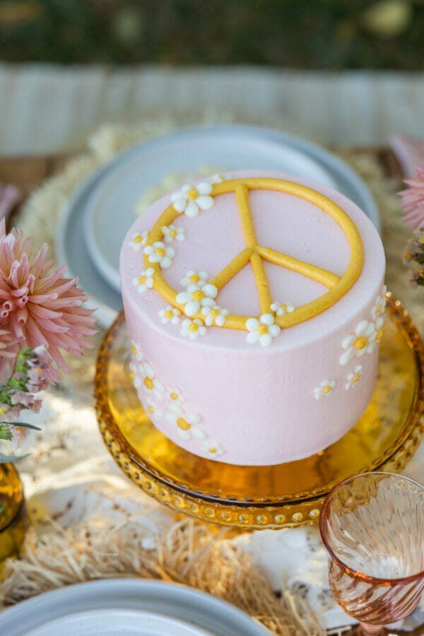 there is a pink cake with a peace sign on it sitting on a gold plate