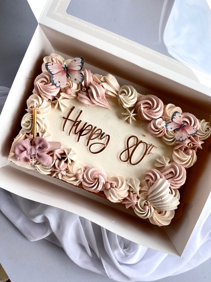 a birthday cake in a box that says happy 80 with butterflies and flowers on it