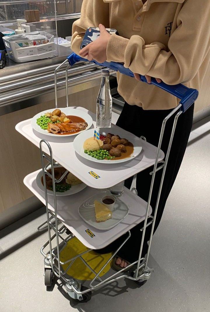 a person standing next to a three tiered cart with food on top of it