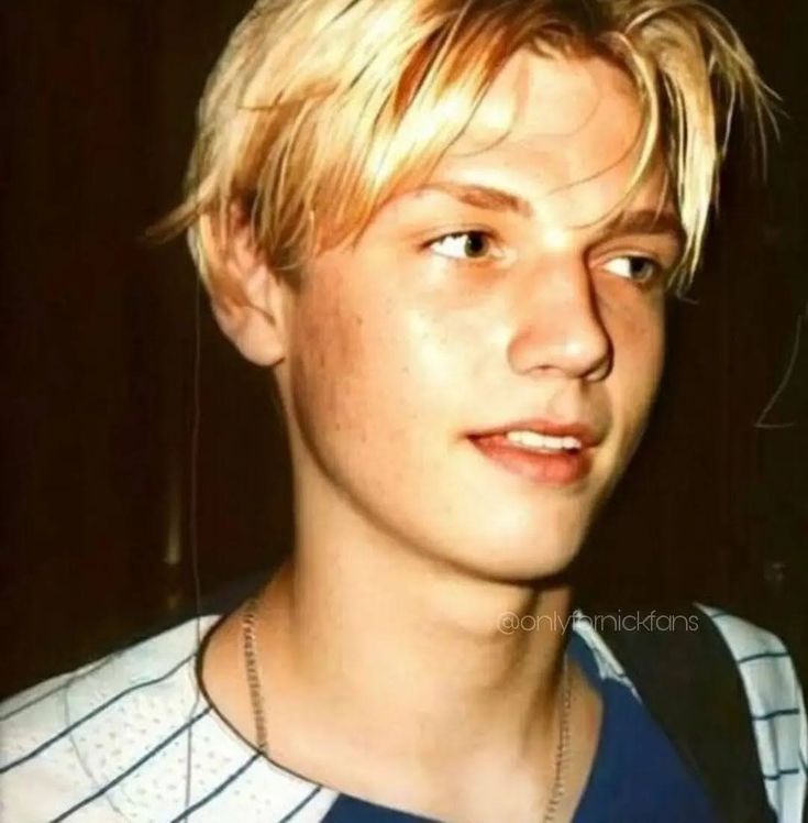 a young man with blonde hair wearing a black and white shirt