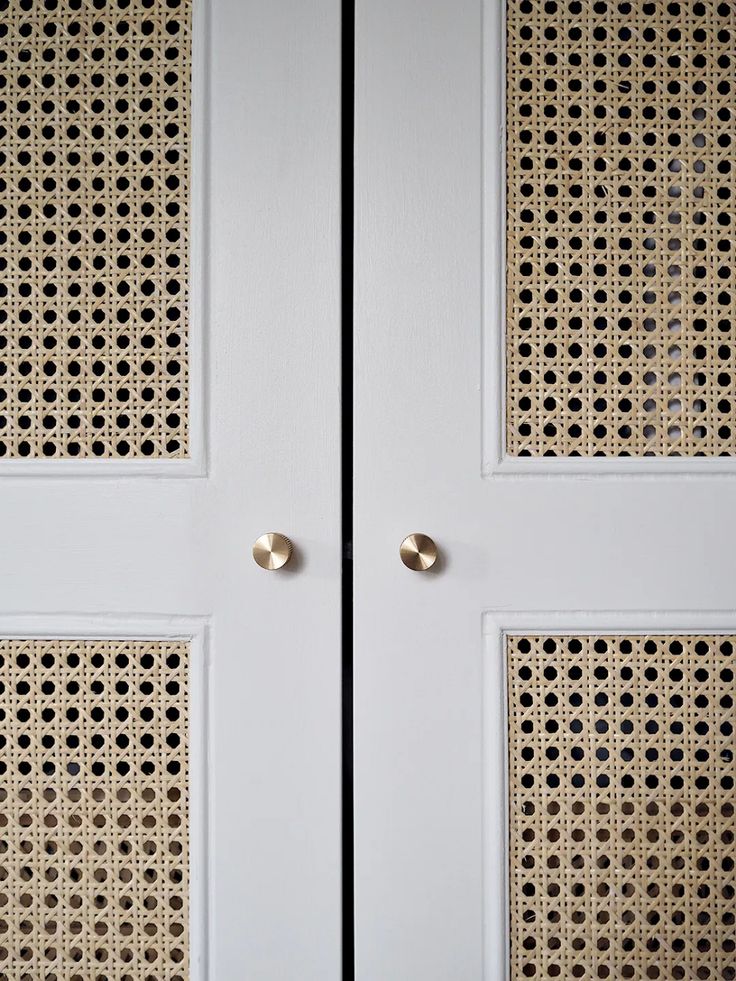 two white doors with gold handles and latticed screens on the front door are shown