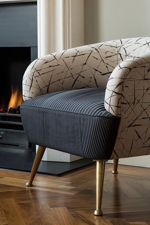 a chair sitting in front of a fire place with wood flooring and a fireplace