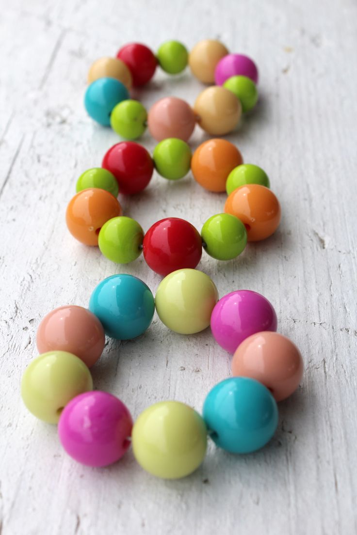 multicolored beads are arranged in the shape of an x on a white surface