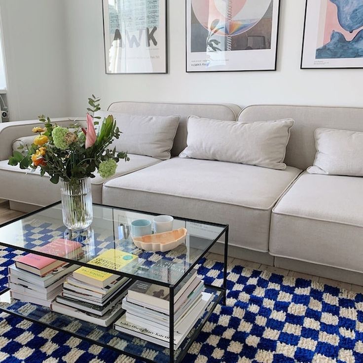 a living room filled with furniture and flowers on top of a glass table next to a couch