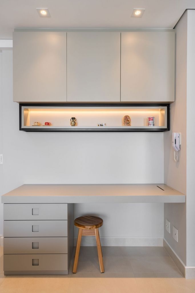 a white desk with drawers and a stool in front of the counter top is illuminated by recessed lighting