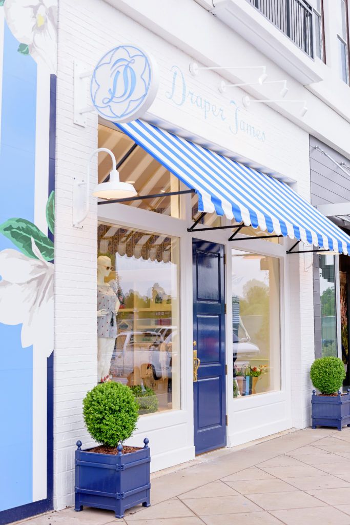 a blue and white striped awning on the front of a store with potted plants