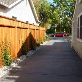 a red car is parked in front of a wooden fence on the side of a street