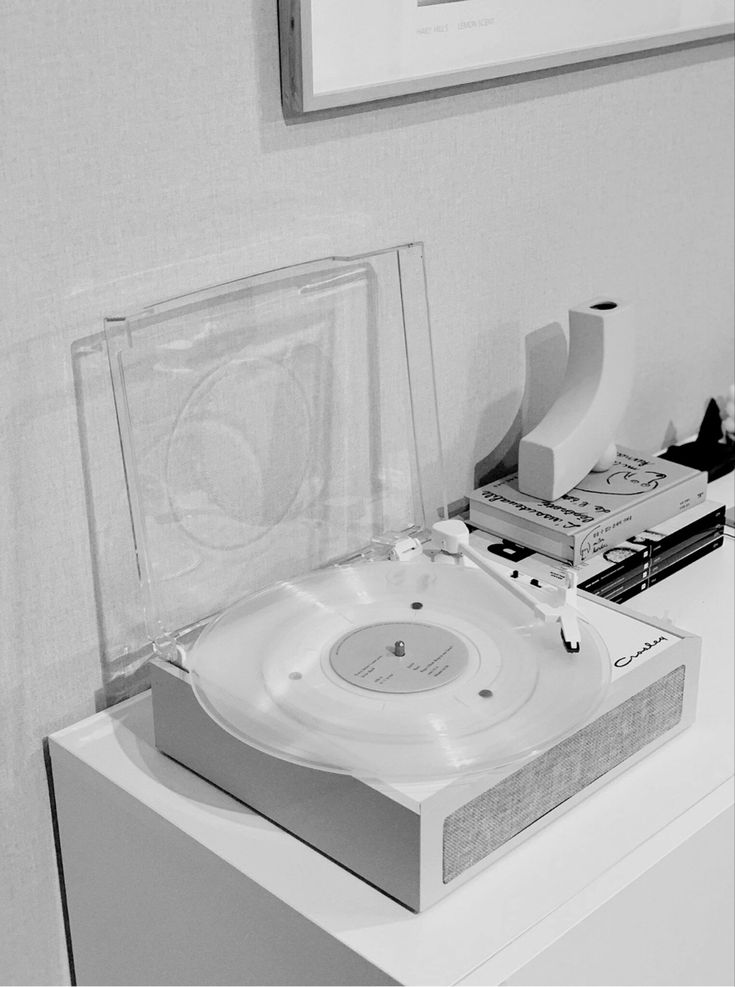 a record player sitting on top of a white table next to a book and other items