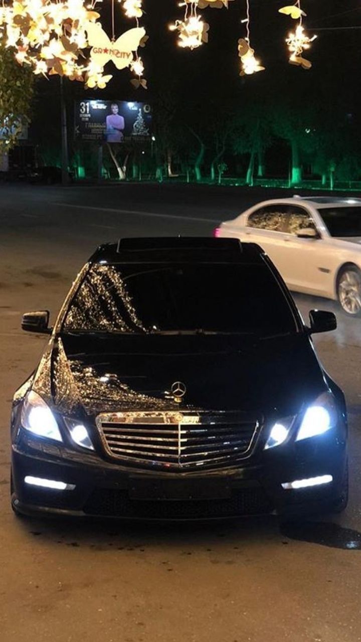 a black car parked on the side of a road next to a bunch of lights