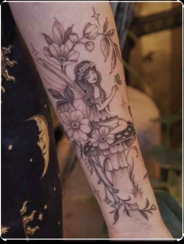 a woman's arm with flowers and a fairy sitting on top of her leg