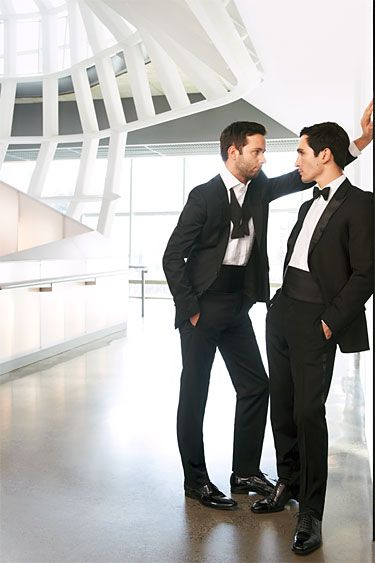 two men in tuxedos standing next to each other and looking at each other