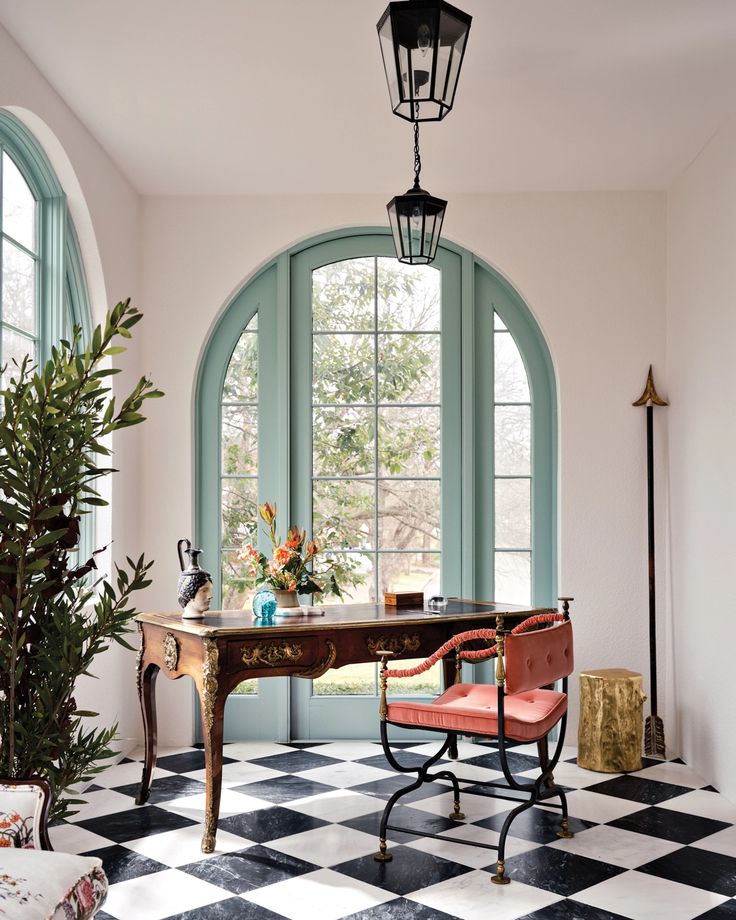 a room with an arched window and checkered flooring in black and white tiles