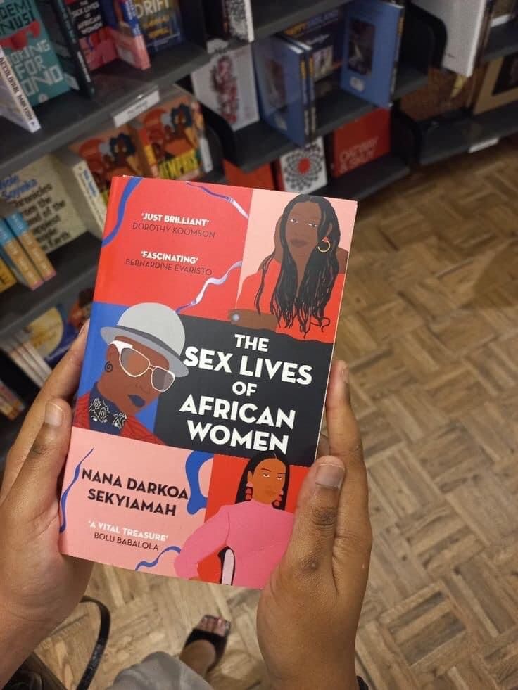 a person holding up a book in front of a bookshelf filled with books