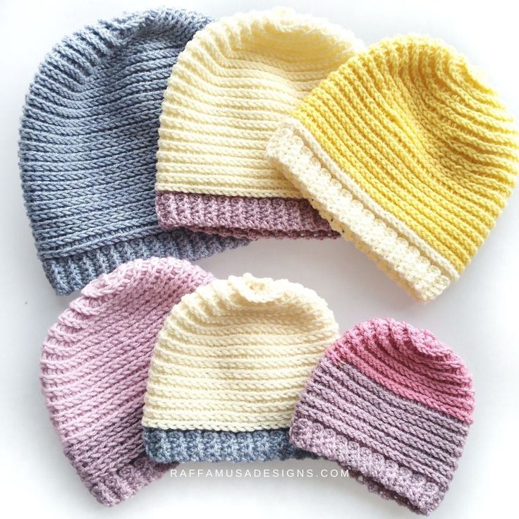 four knitted hats in different colors on a white surface