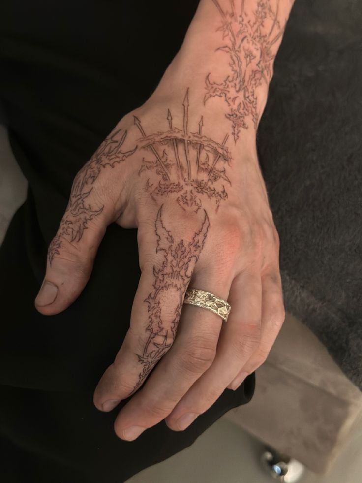 a person's hand with tattoos on it and a gold band around the wrist