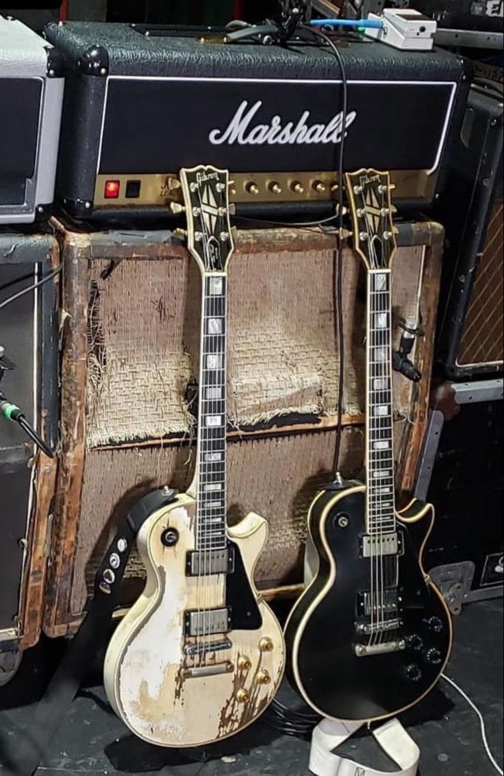 two guitars are sitting next to each other in front of an amplifier and amps