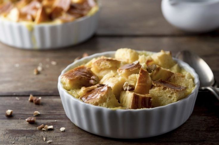 two bowls filled with food sitting on top of a wooden table next to spoons