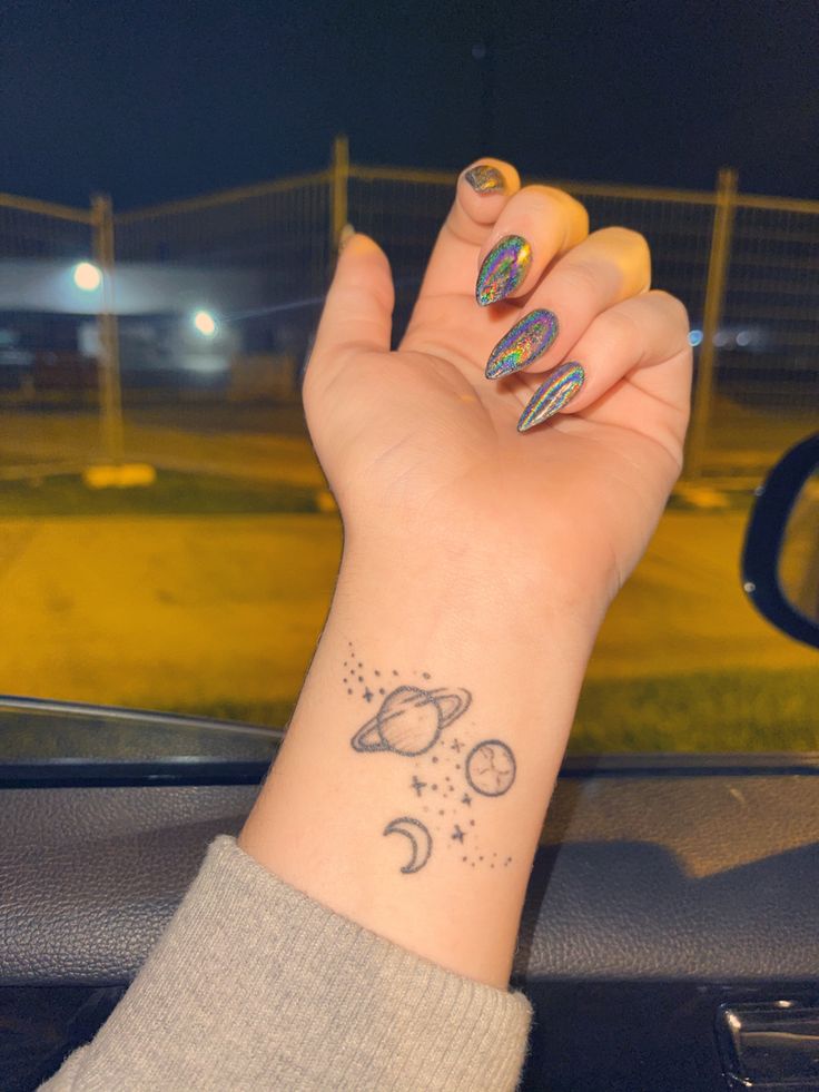 a woman's hand with a small tattoo on her left wrist and the moon and stars