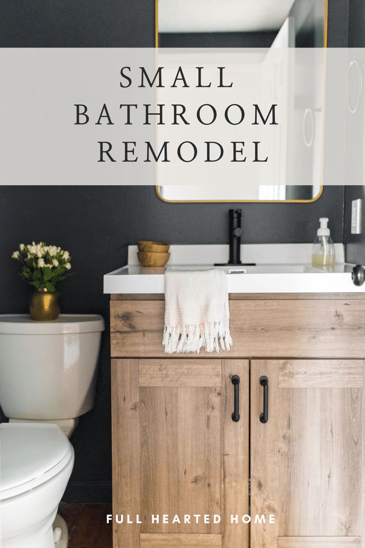 a white toilet sitting next to a wooden cabinet under a bathroom mirror with a gold framed mirror above it