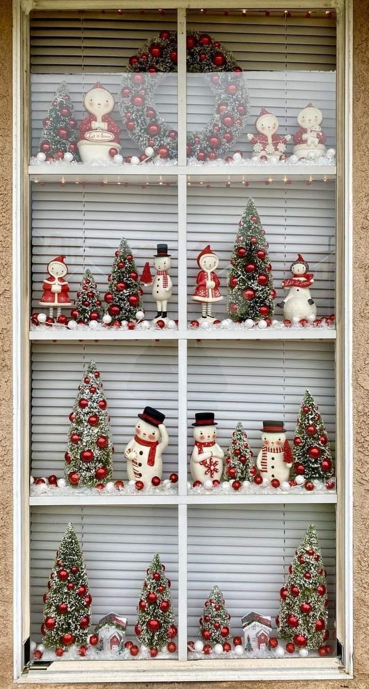 a display case filled with christmas decorations and snowman figurines in front of a window