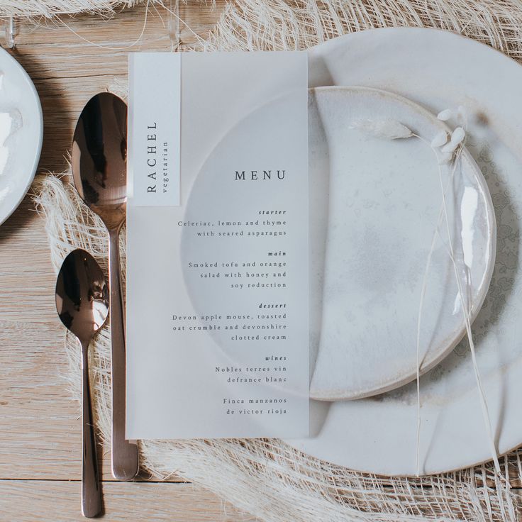 a table setting with place settings and silverware on it, including a menu card