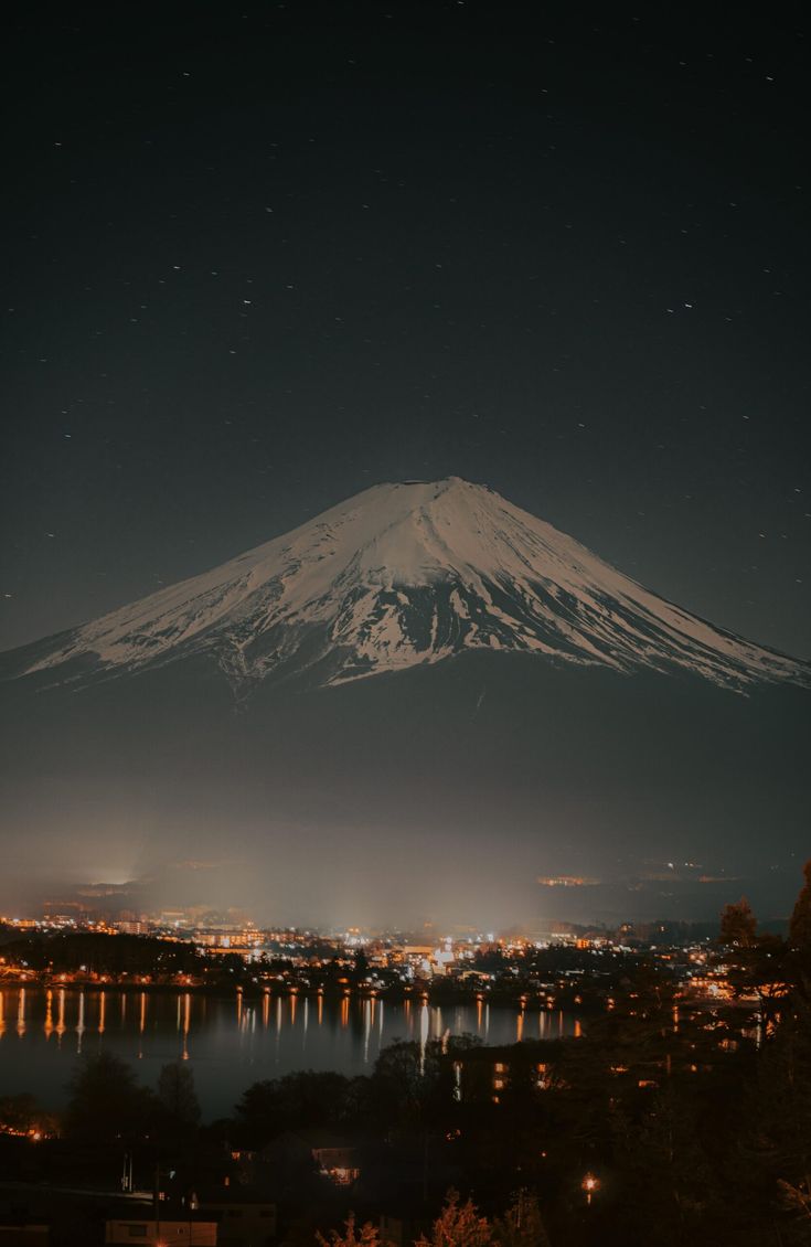 a night view of a mountain with lights on it's top and water below