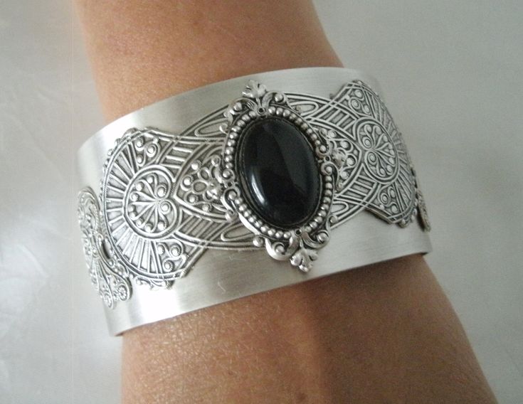 This beautiful silver plated cuff bracelet has a black onyx stone set on silver plated embellishments and silver plated gothic wings on the sides. Adjustable. Ornate Metal Jewelry Collectible, Elegant Metal Cuff Bracelet, Elegant Adjustable Metal Cuff Bracelet, Victorian Style Metal Jewelry With Jewels, Ornate Metal Bracelet Jewelry, Elegant Metal Cuff Bracelet For Formal Occasions, Elegant Cuff Jewelry With Intricate Design, Metal Bangle With Jewels, Handmade Adjustable Antique Silver Jewelry