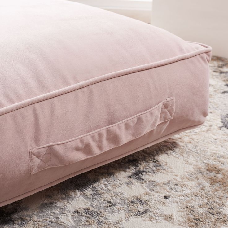 a pink pillow sitting on top of a rug