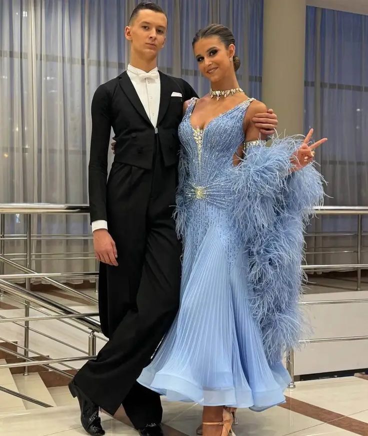 a man in a tuxedo and a woman in a blue dress pose for a photo