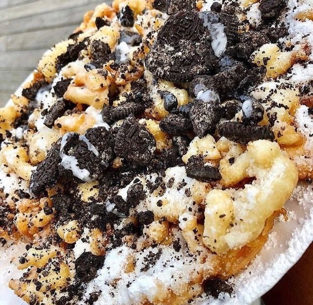 a white plate topped with dessert covered in chocolate chips and oreo cookies on top of powdered sugar