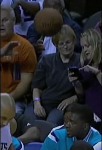 people sitting in the bleachers looking at their cell phones while one person is holding a basketball