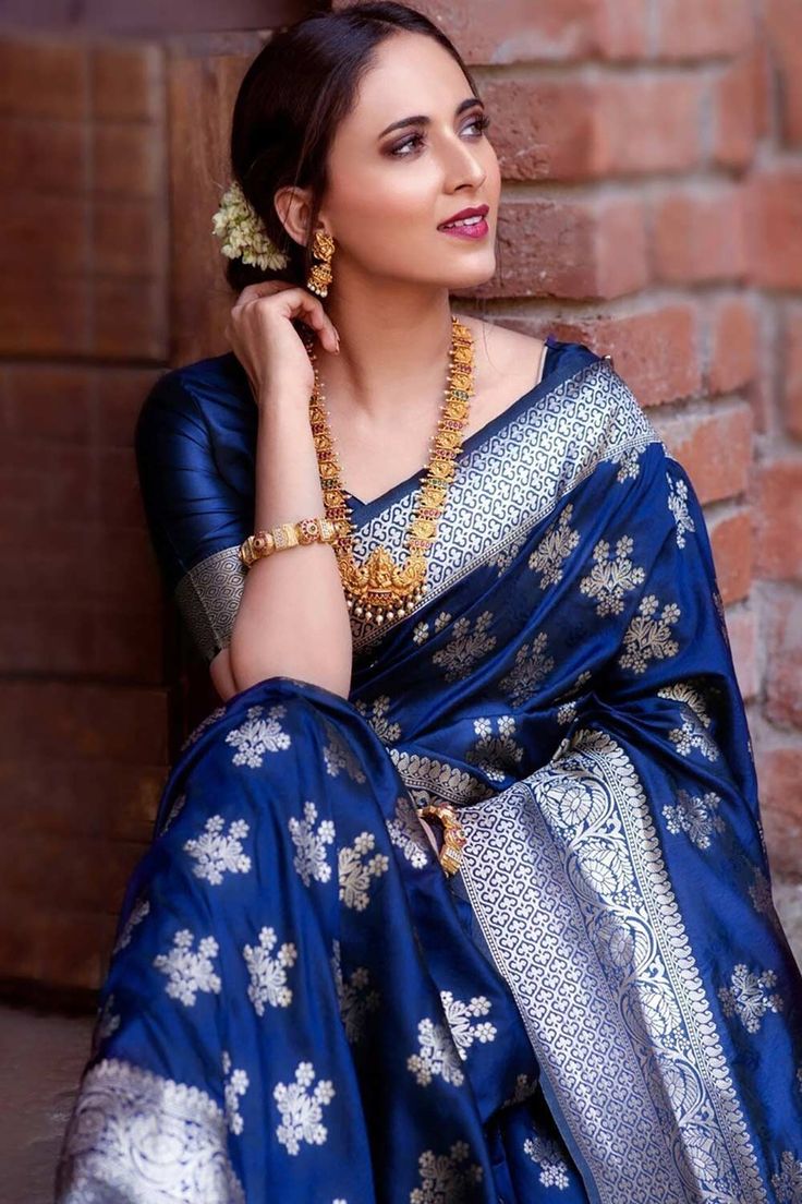 a woman wearing a blue sari and gold jewelry