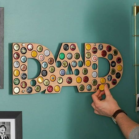 a man is holding up a wooden sign that says dad with buttons on the letters