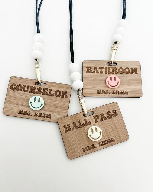 three wooden luggage tags with smiley faces on them, one for bathroom and the other for hall pass