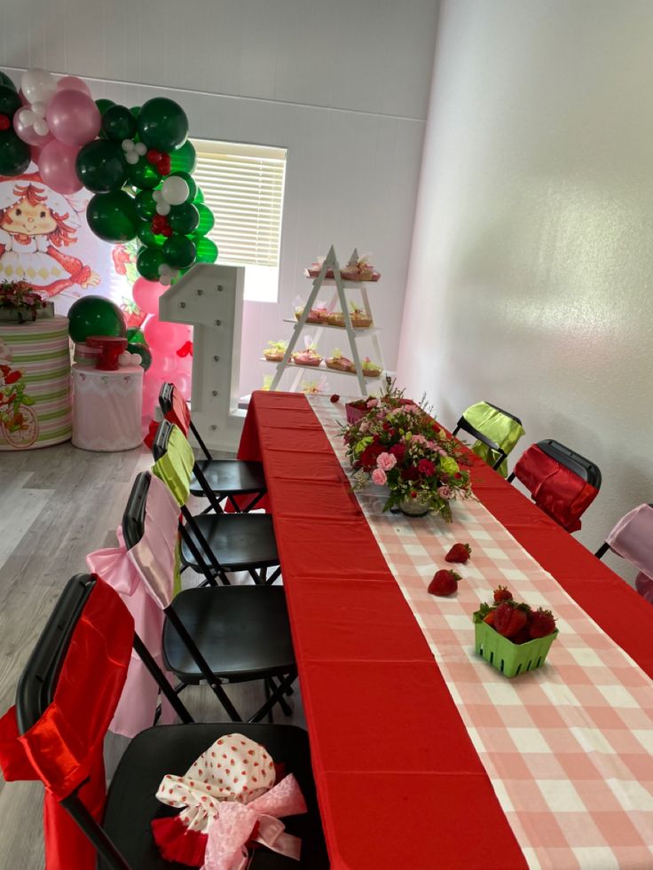 a long table with red and white checkered cloths on it, surrounded by black folding chairs