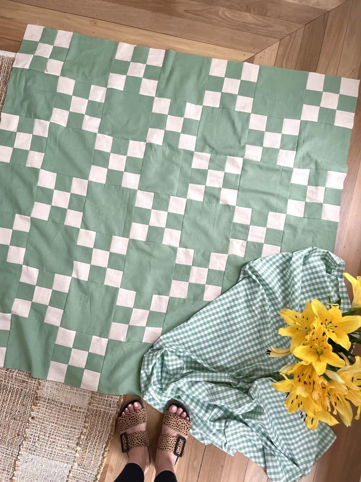 a person standing next to a green and white checkered blanket with yellow flowers on it