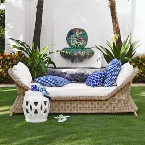 a white couch sitting on top of a lush green field next to a palm tree