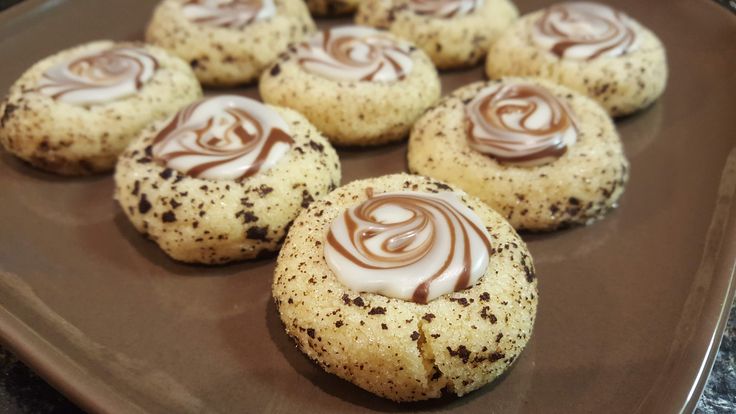 chocolate chip cookies with white frosting and sprinkles on a brown plate